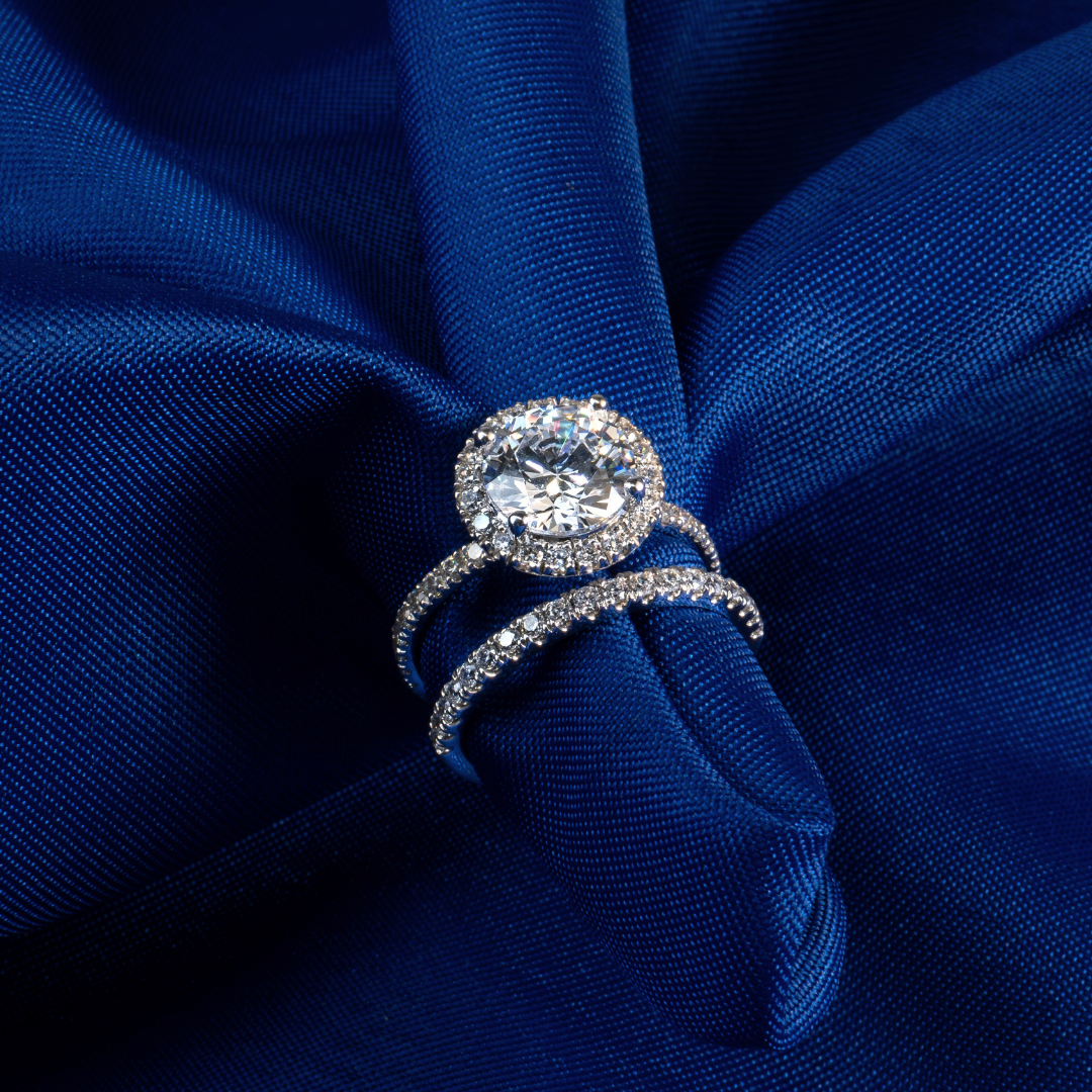 A diamond engagement ring and a wedding band displayed on luxurious, deep blue fabric