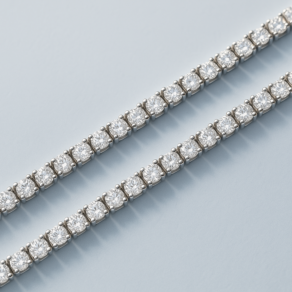 A close-up of two four-prong tennis bracelets placed side by side, displayed on a light blue background