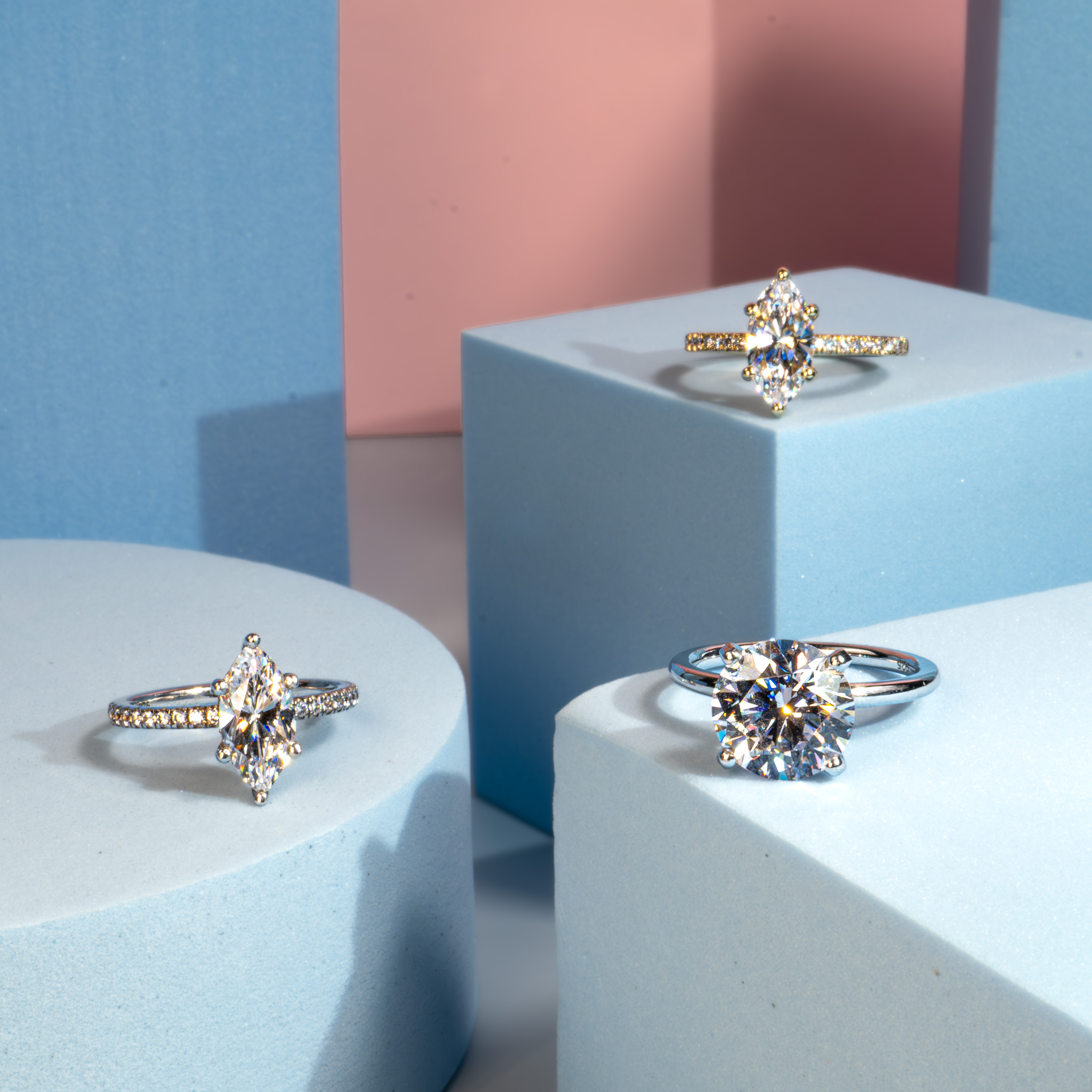 Elegant diamond engagement rings in various cuts and settings displayed on pastel stands from Rare Carat, the best place to buy diamond jewelry