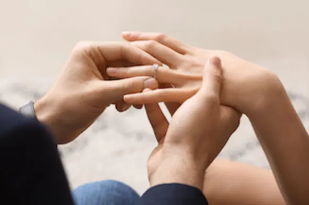 Man putting a ring on the women's finger after Valentine's Day proposal