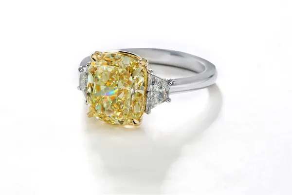 Image of a large yellow cushion cut diamond ring with trapezoid side stones in white gold