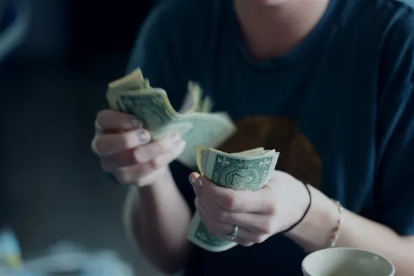 Woman counting money with a coffee cup