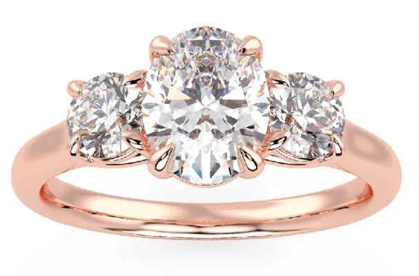 An oval center stone with two round side diamonds making up the three stone ring in rose gold 