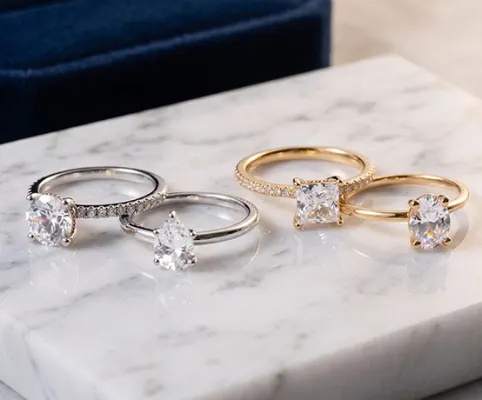 Oval-cut diamond engagement ring with a pavé diamond yellow gold band, displayed on a light background