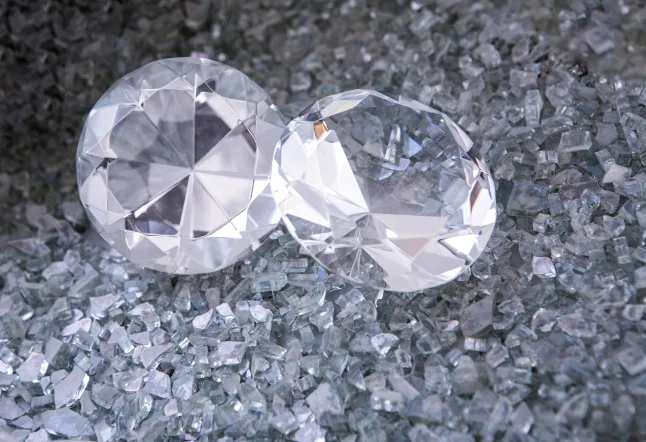 Two round cut diamonds resting on a bed of crushed glass