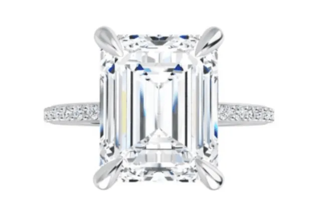 Emerald cut diamond in a prong setting with a pave band 