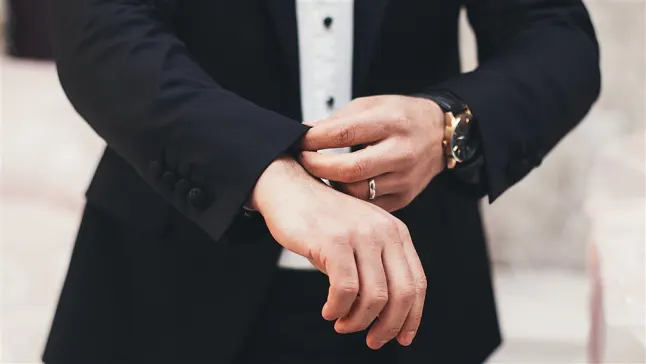 man in suit adjusting his cuff, with a wedding band