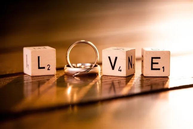 scrabble letters spelling out love with wedding ring in the middle for the "o"
