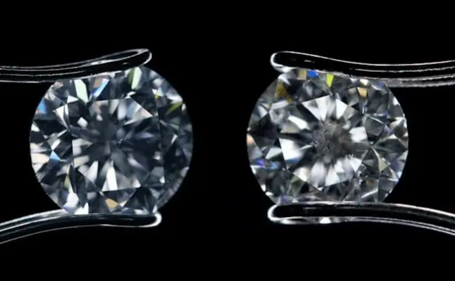 Close-up of two diamonds held by tweezers