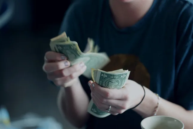 Woman counting money with a coffee cup