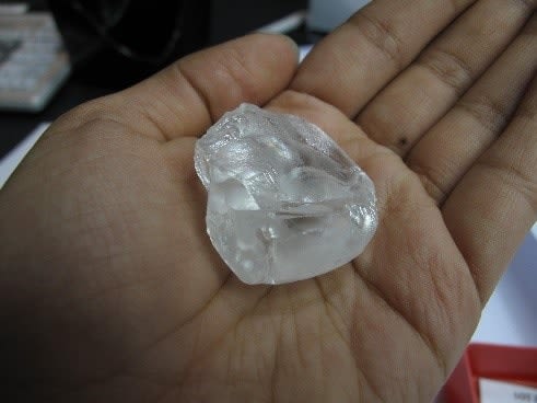 Close-up of a hand holding a rough diamond