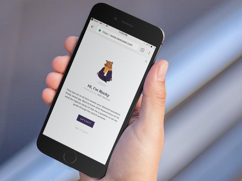 Close-up of a hand holding a smartphone displaying Rare Carat's chatbot, Rocky, on the screen