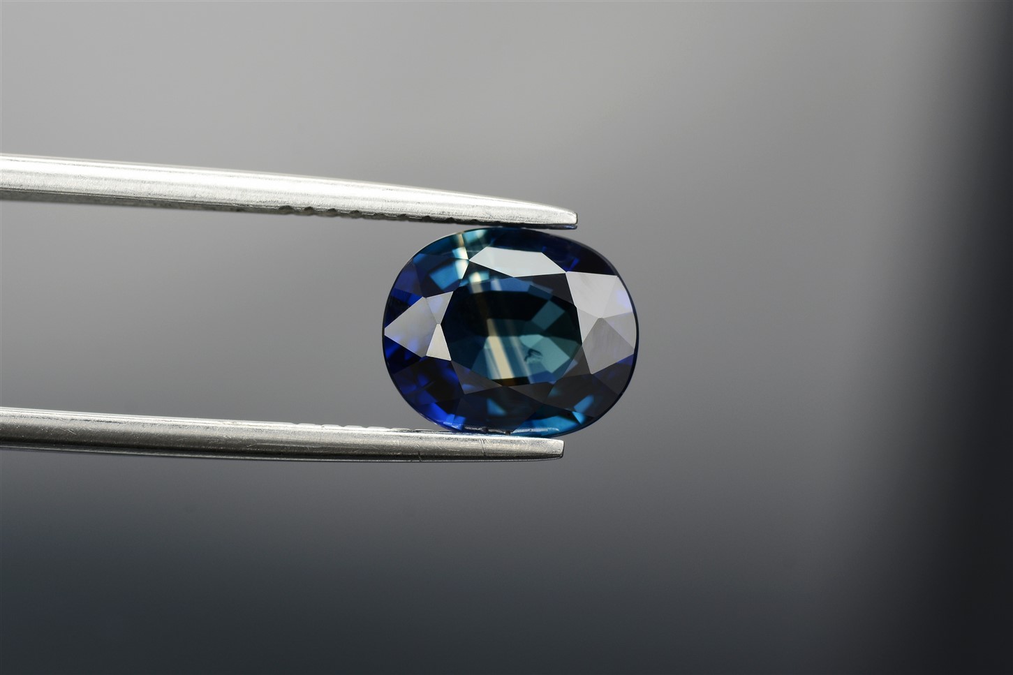 A close-up of a sapphire held by tweezers