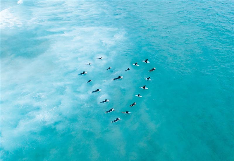 Bird’s-eye view of surfers forming a heart shape in the ocean