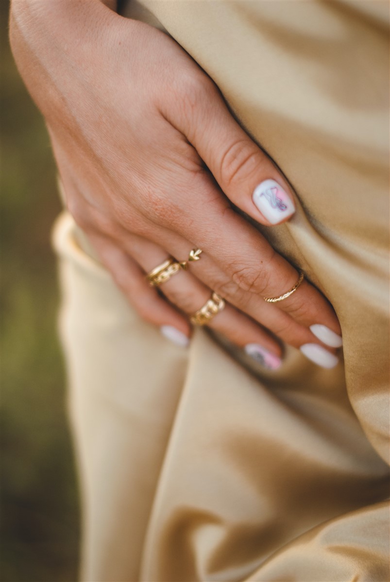 A close-up of a woman's hand adorned with trendy, minimal gold stackable rings