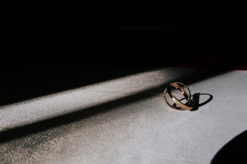A gimmal gold ring resting on a table, illuminated by sunlight, showcasing its shine and intricate design