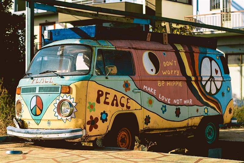 A broken-down vintage minivan covered in colors and symbols representing the 1970s retro hippie vibe