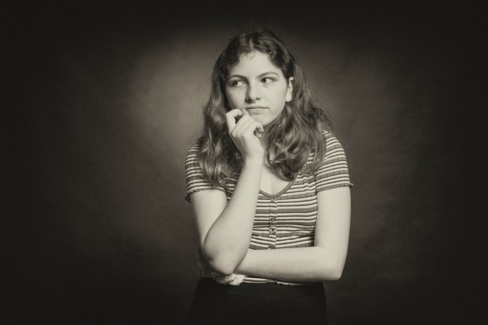 A woman resting one hand on her chin, appearing deep in thought as she considers a decision