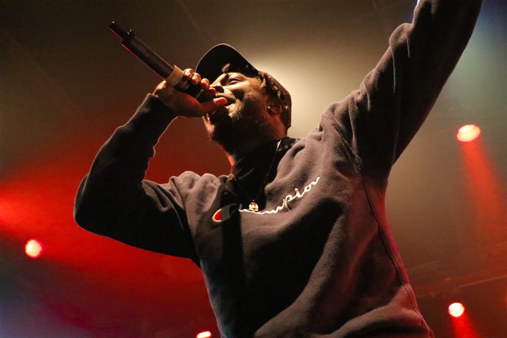 A male performer on stage passionately singing into a microphone
