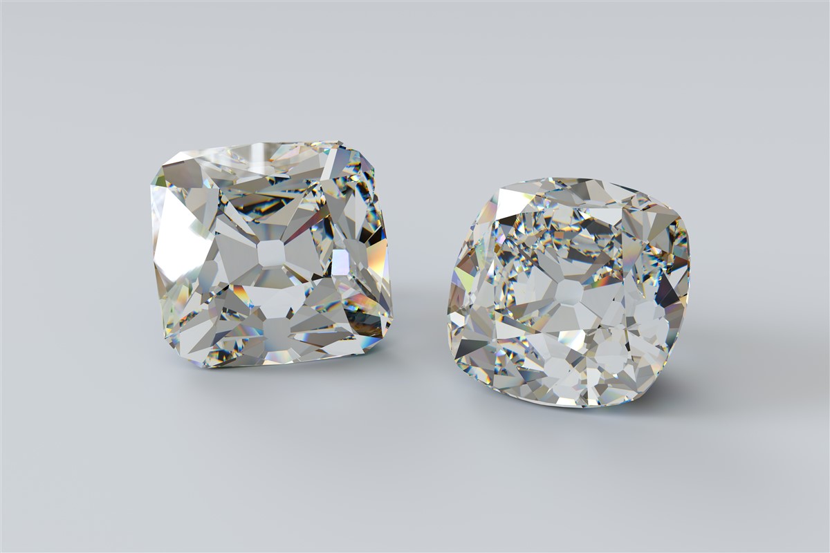 Two old mine cut diamonds are displayed on a light gray background, exuding elegance and luxury