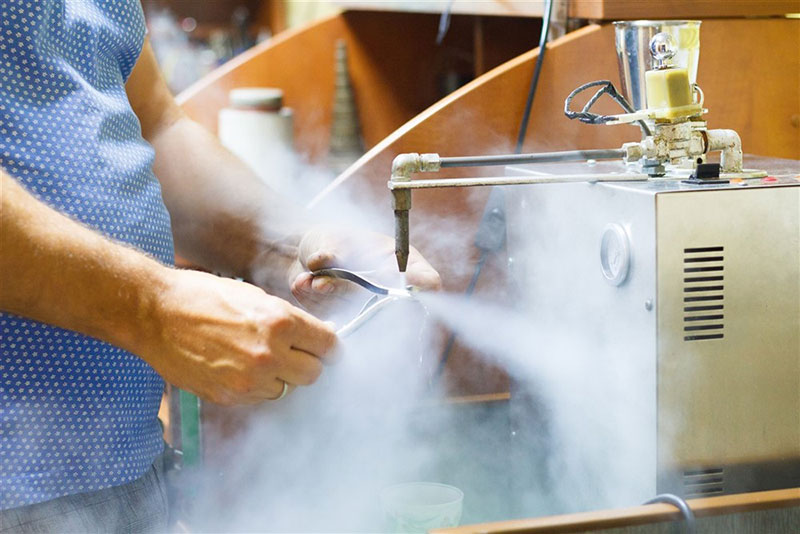 A jeweler steaming a piece of jewelry with a high pressure steam machine