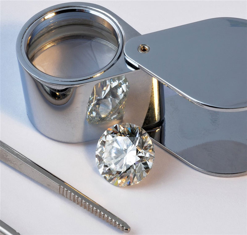 A jewelers loupe with a round brilliant diamond and tweezers