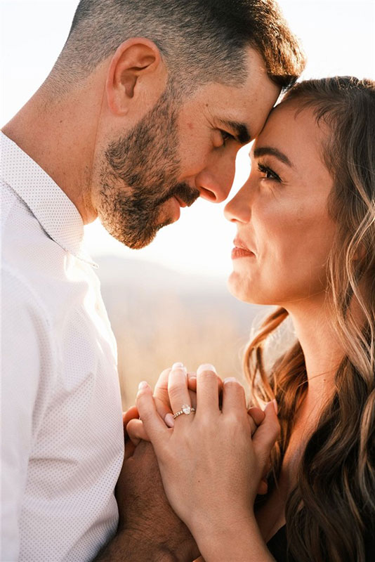 Couple holding hands, woman wearing diamond engagement ring