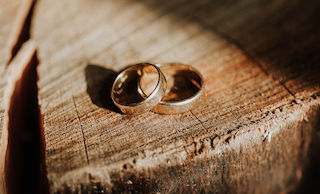 A wedding band ring set displayed on a wooden surface, illuminated by warm sunlight