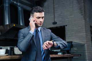 A man looking at his wristwatch while on phone