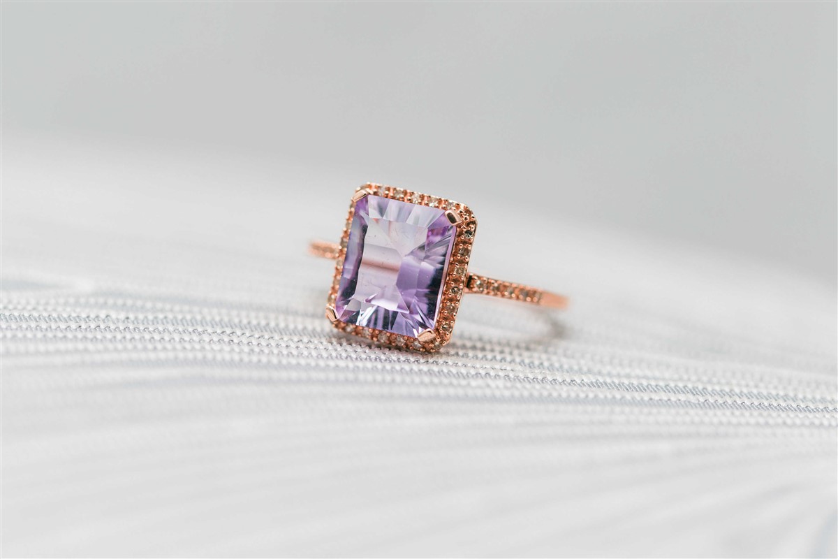 An amethyst ring in a rose gold setting, displayed on a white surface