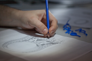 A close-up of hands making jewelry design sketch