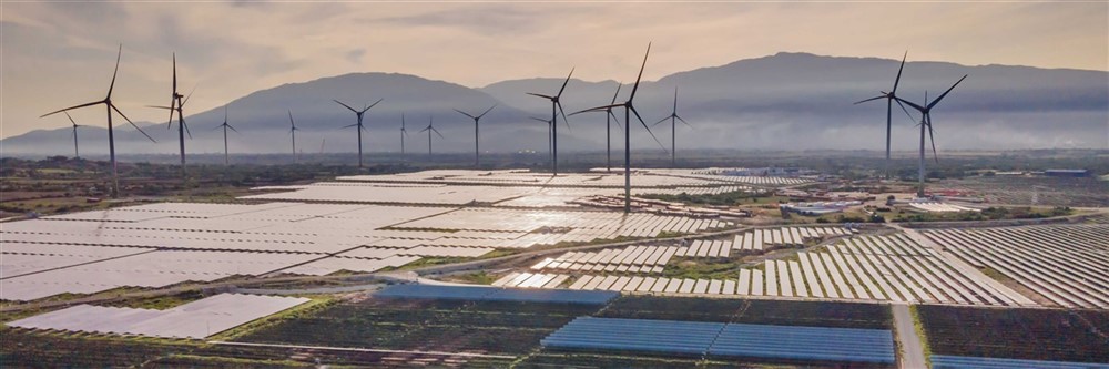 A landscape showcasing a wind farm featuring multiple wind turbines alongside rows of solar panels, highlighting renewable energy sources