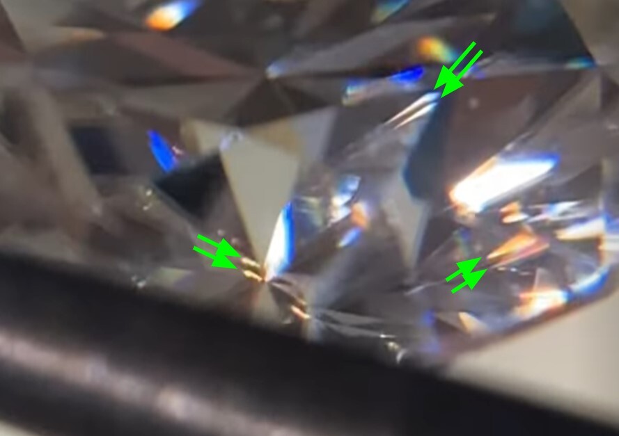 Green cursors pointing to a moissanite's optical double refractions